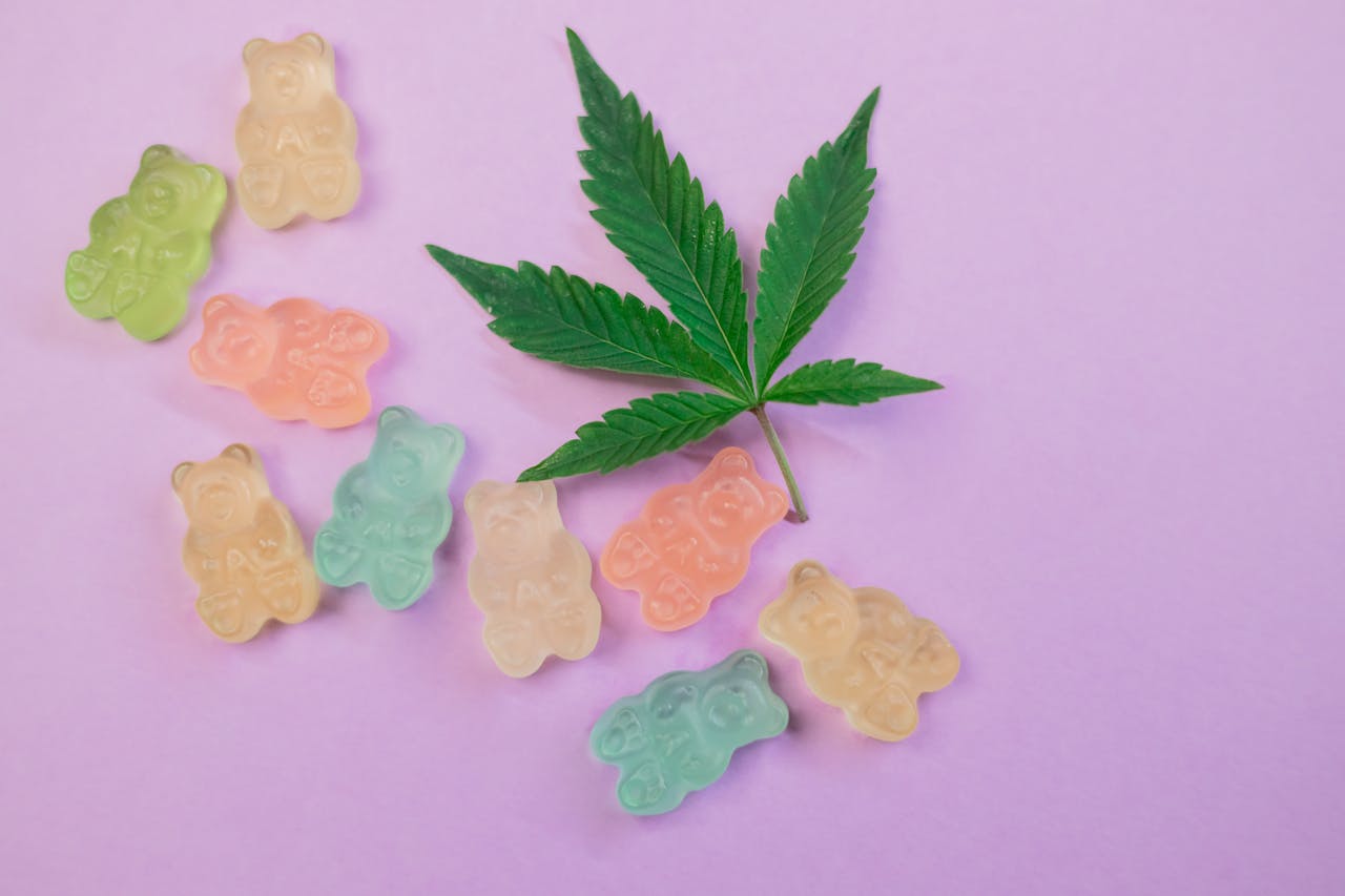 Services Vibrant gummy bears and a cannabis leaf on a pastel background, symbolizing cannabis edibles.